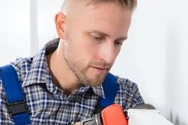 Mann montiert eine Heizung. Zählersetzung und Inbetriebnahme, SWS Netze.