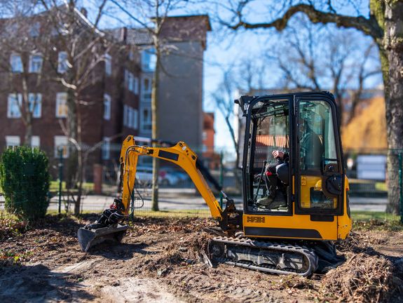 Arbeiter bedient einen gelben Bagger an einem sonnigen Herbsttag. SWS Netze GmbH